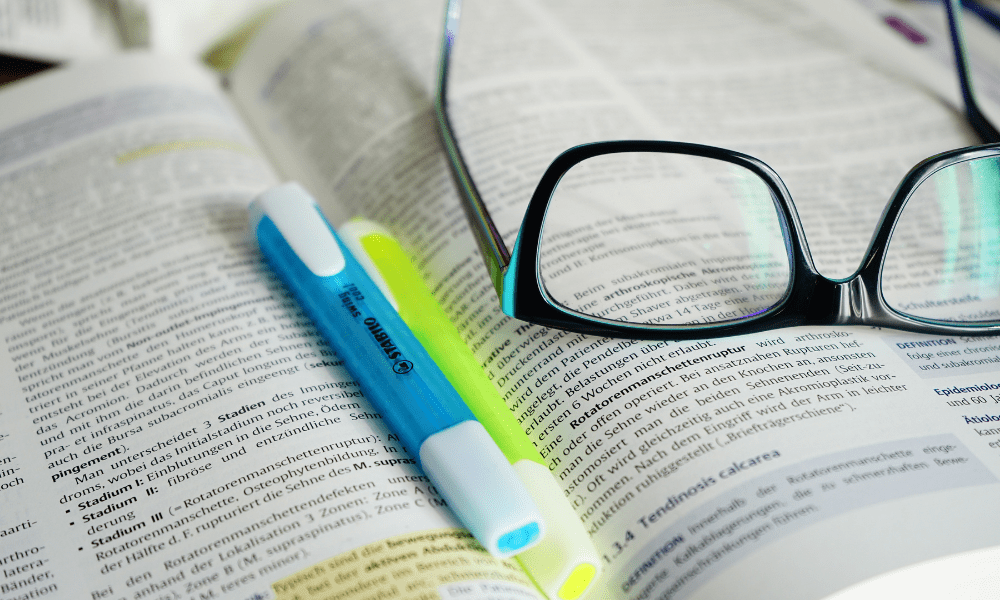 open book with highlighters in center and glasses to side