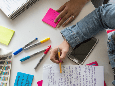 table with papers, markers, notes, two arms visible