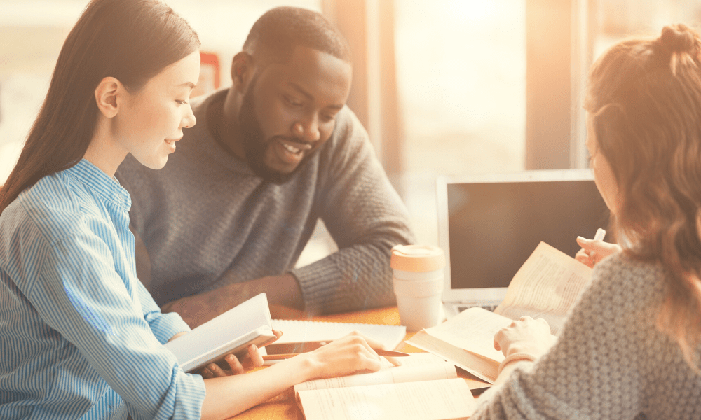 two females and male sit at table looking at paperwork