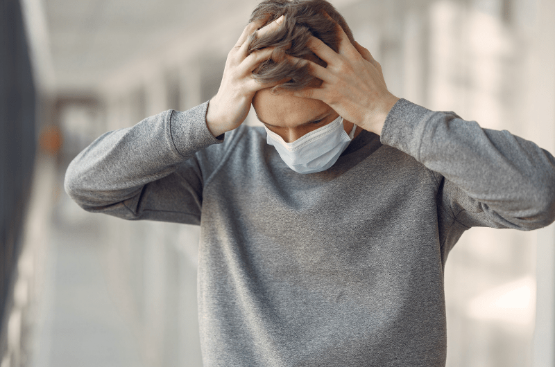 male with mask holding head in angst